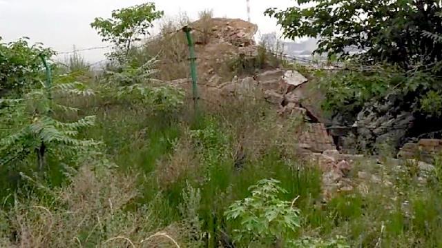 Ein Stacheldrahtzaun wurde hinter dem Tempel installiert; ein dichtes Gestrüpp von Unkraut hat sich am Ort der Ruine ausgebreitet (aktuelles Foto)