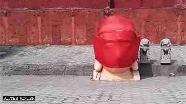 Der Kopf der zerstörten Buddha-Statue wurde in roten Stoff gewickelt.