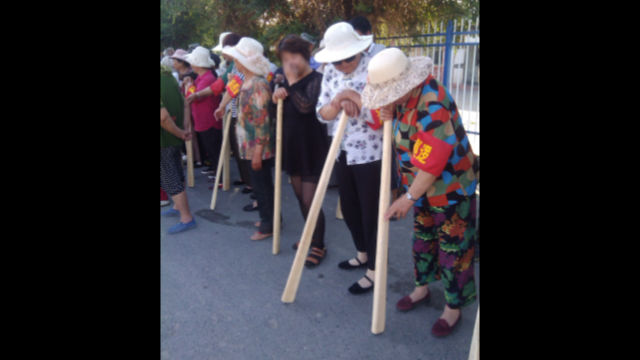 Die Bewohner eines Stadtviertels von Xinjiang tragen Holzschläger, wenn sie an „Anti-Terror-Übungen“ teilnehmen.